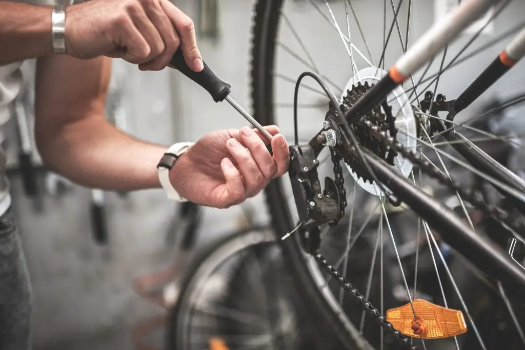 Close up shot on male hands inside bicycle store while repairing the gearshift on rear wheel of a mountain bike